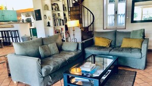 A living room with two grey sofas, a glass coffee table, and a small round ottoman. - Au Coeur du Banzeau (Noirmoutier-en-l'Île)