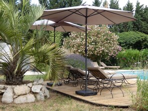 A poolside area with lounge chairs and a pergola with umbrellas.