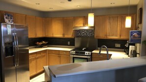 Une cuisine moderne avec des meubles en bois, des appareils en acier inoxydable, un four encastré et un îlot central.