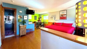 A hotel room with a bed, a desk, a chair, a TV, and a bathroom.