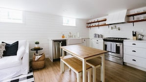 A modern kitchen with white cabinetry, a wooden dining table, and a built-in oven.