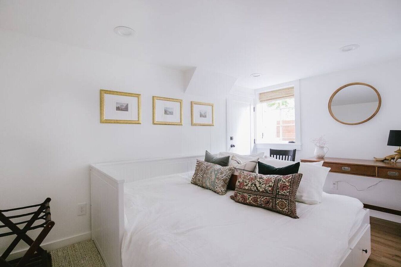 A bedroom with a bed, a dresser, a chair, and framed pictures on the wall.