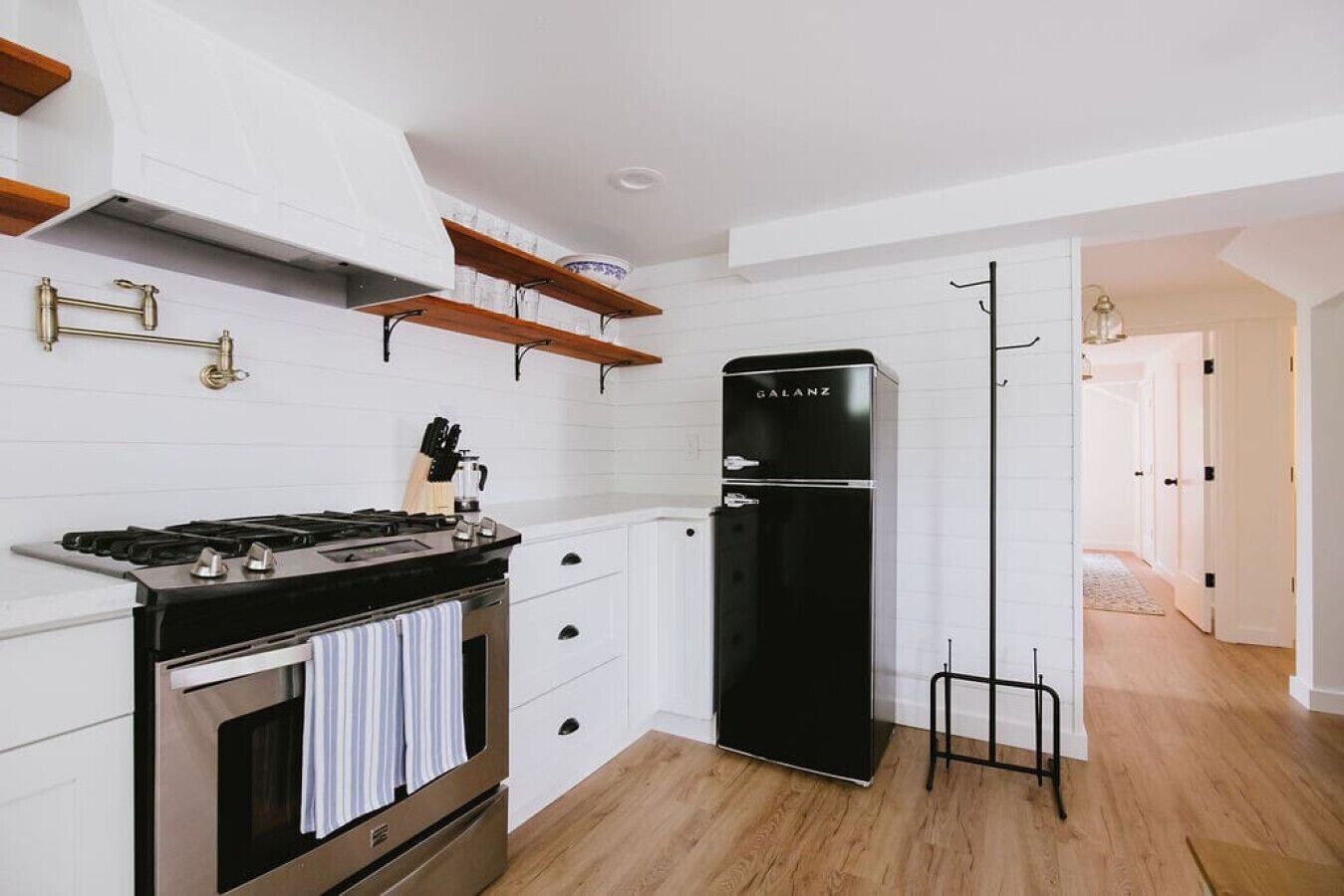 A compact kitchen with white cabinetry, a black stove, and a black refrigerator.