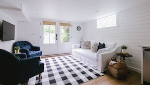 A room with a white sofa, a blue armchair, and a checkered rug.