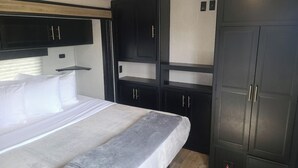 Un dormitorio con cama, un edredón gris y armarios negros.