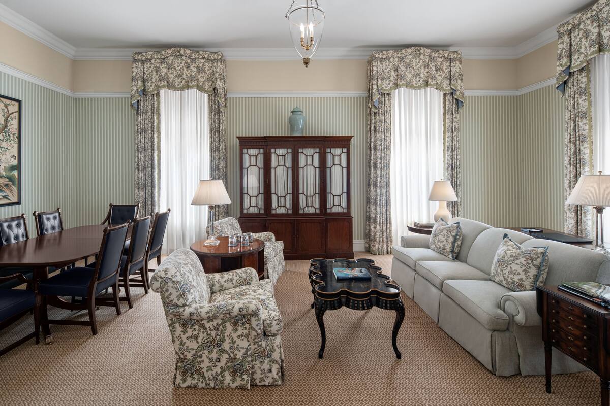 A traditional living room with a dining area, featuring a sofa, chairs, a coffee table, and a cabinet.