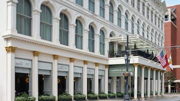 Experience the classic charm of the Capital Hotel, featuring arched windows, a balcony, and elegant gold accents.