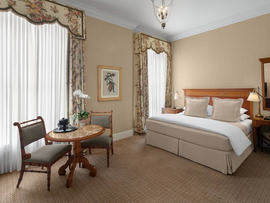 Una habitación de hotel con cama, escritorio, silla, mesa y una araña.