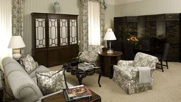 A living room with a sofa, armchairs, a coffee table, a cabinet, and a decorative screen.