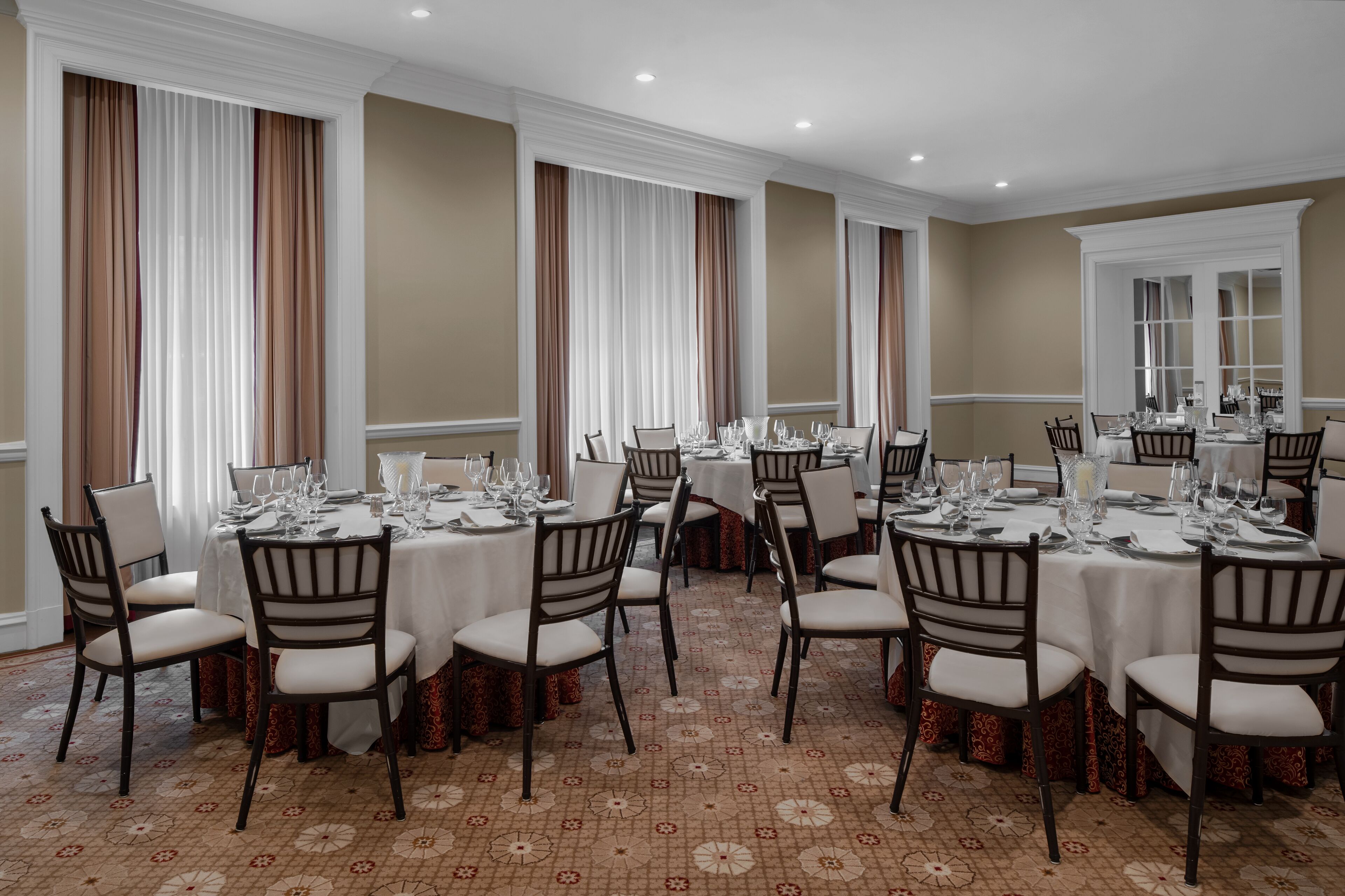 A banquet hall with round tables set for dining, equipped with chairs and table settings.