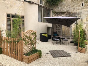 Relax in a serene outdoor seating area surrounded by lush greenery and a stone wall.