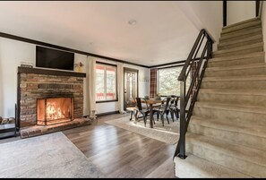 Cozy living area with a fireplace, dining table, and staircase.