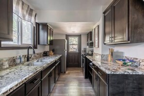 Kitchen features a central island with a sink, refrigerator, and microwave.