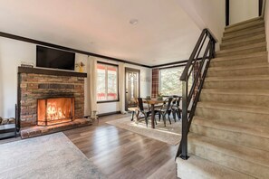Cozy living area with a fireplace, dining table, and staircase.