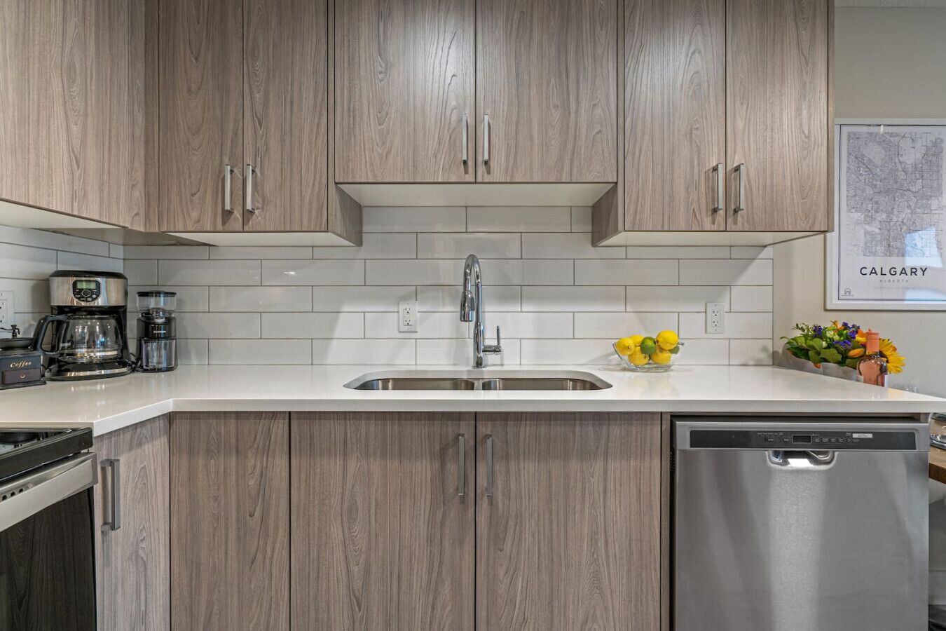 A kitchen with wooden cabinets, a stainless steel sink, a coffee maker, and a dishwasher.