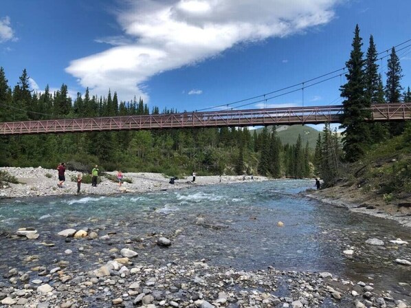 Un río con rocas y un puente al fondo.