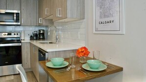 A modern kitchen with stainless steel appliances, a wooden countertop, and a framed map of Calgary.