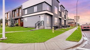 A modern multi-story residential building with a flat roof, a well-maintained lawn, and a visible fire hydrant. - Modern 3Br Altadore Home Near Downtown (Calgary)