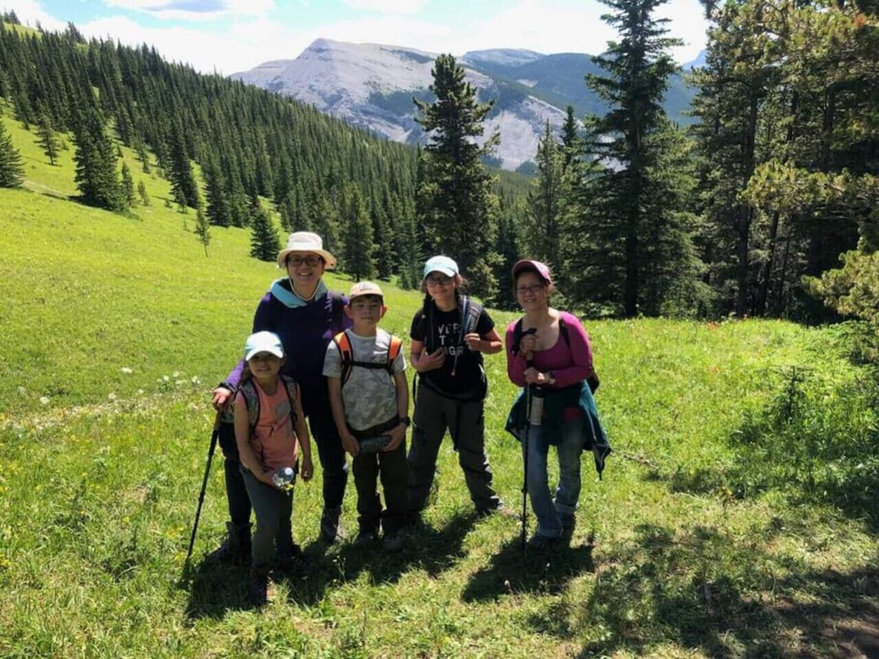 A group of people standing in a grassy field with mountains in the background.