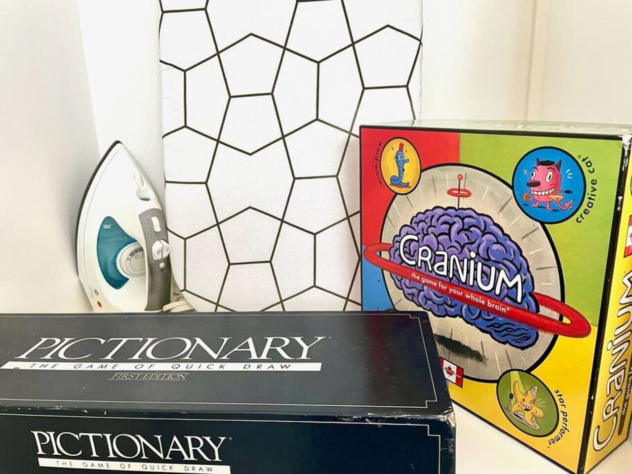 Et spilæske med teksten 'CRANIUM' og et spil kaldet 'PICTIONARY' på et bord.
