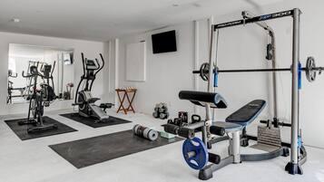 A home gym with various exercise equipment including a treadmill, elliptical, weight bench, and a squat rack.