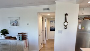 A modern kitchen with a stainless steel refrigerator, wooden flooring, and a white cabinet. - Newly renovated Oceanside condo with easy access to the pool and beach! (Ocean City)