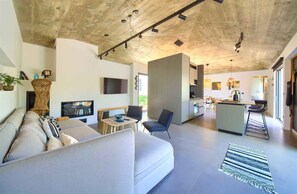 A modern living room with a sofa, a TV, and a dining area with a table and chairs.