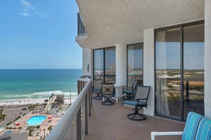 Un balcon avec vue sur l’océan, équipé de chaises et d’une piscine.