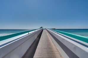 A long, straight bridge with a wooden walkway, leading to a body of water under a clear sky. - Free Beach SRVC! Gorgeous Ocean & Bay Views! Free Beach Bonfires M/F nts (Miramar Beach)