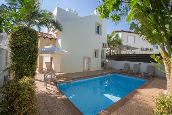 Relax by the pool surrounded by lush greenery and comfortable lounge chairs.