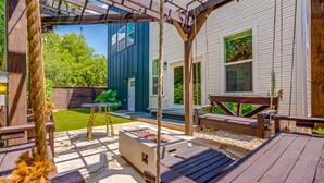 Una terraza de madera con un columpio, un banco y una mesa.