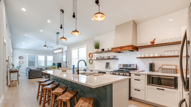 Una cocina moderna con una isla grande, taburetes de madera y electrodomésticos integrados.
