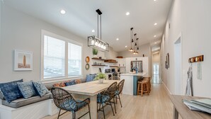 Una cocina moderna con una isla central, electrodomésticos integrados y una zona de comedor con sillas de mimbre.