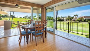 Un balcón amplio con una mesa y sillas para comer, con vistas a un campo de golf.