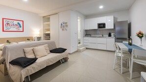 Un appartamento moderno e luminoso con angolo cottura, zona pranzo e soggiorno con divano e letto.