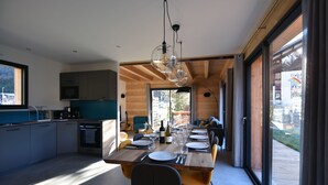 A modern kitchen with a dining area, large windows, and a view of the outdoors. - Chalet for 8 people with Terrace / Garden / Spa - 5 rooms - 4 bedrooms (Montriond)