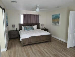 A bedroom with a bed, nightstands, a ceiling fan, a window with curtains, and a painting on the wall. - Private Newly Renovated Home - Short Walk to Beach, Food, Shopping & More!!! (Lauderdale-by-the-Sea)