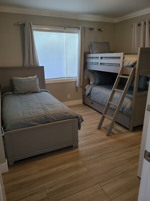 Een slaapkamer met een enkel bed, een stapelbed en een ladder.