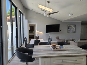 A modern kitchen with a large island, dining chairs, a flat-screen TV, and a ceiling fan. - Private Newly Renovated Home - Short Walk to Beach, Food, Shopping & More!!! (Lauderdale-by-the-Sea)