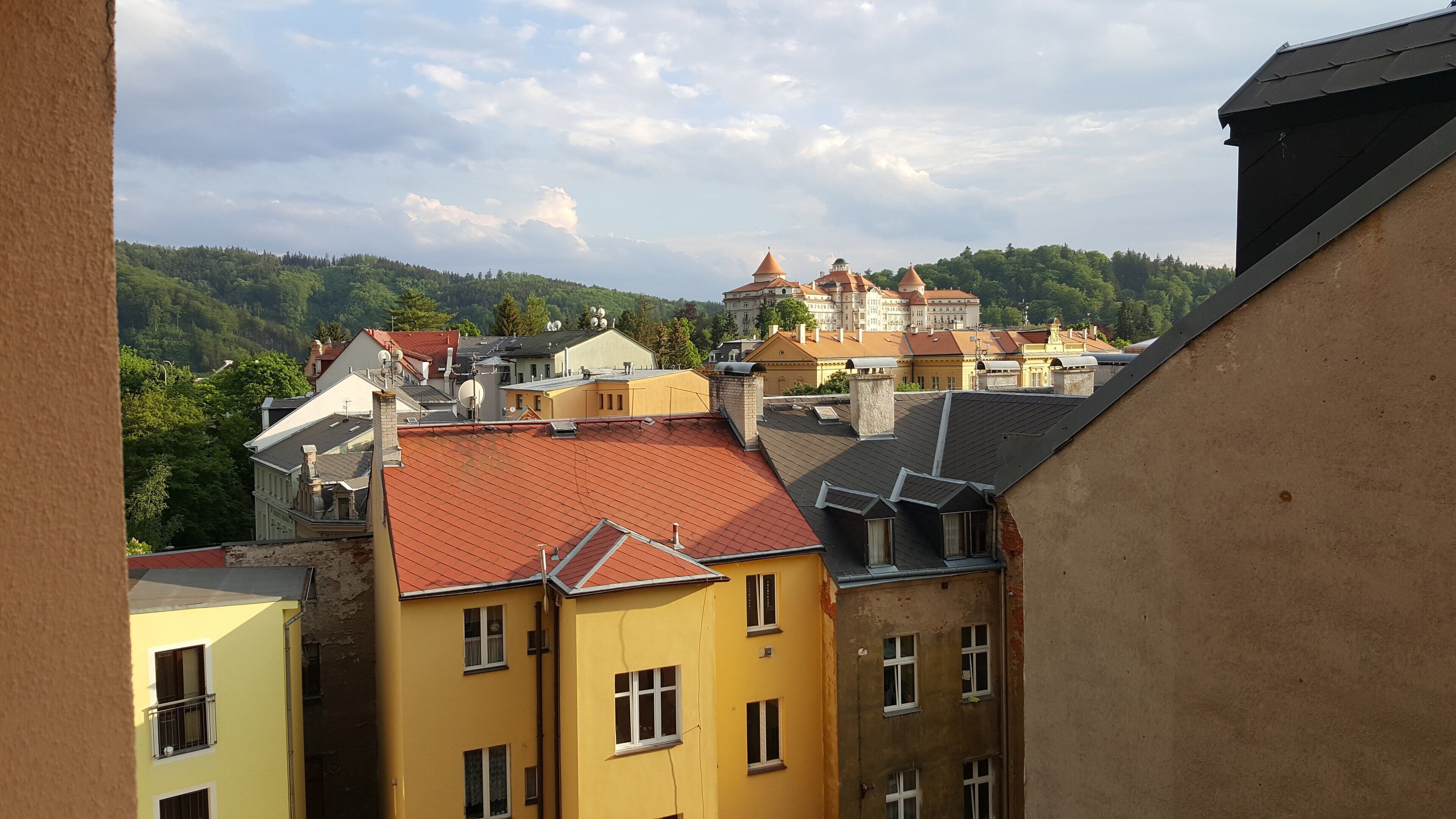 A view of a town with buildings, including a prominent yellow building with multiple windows and a red roof.