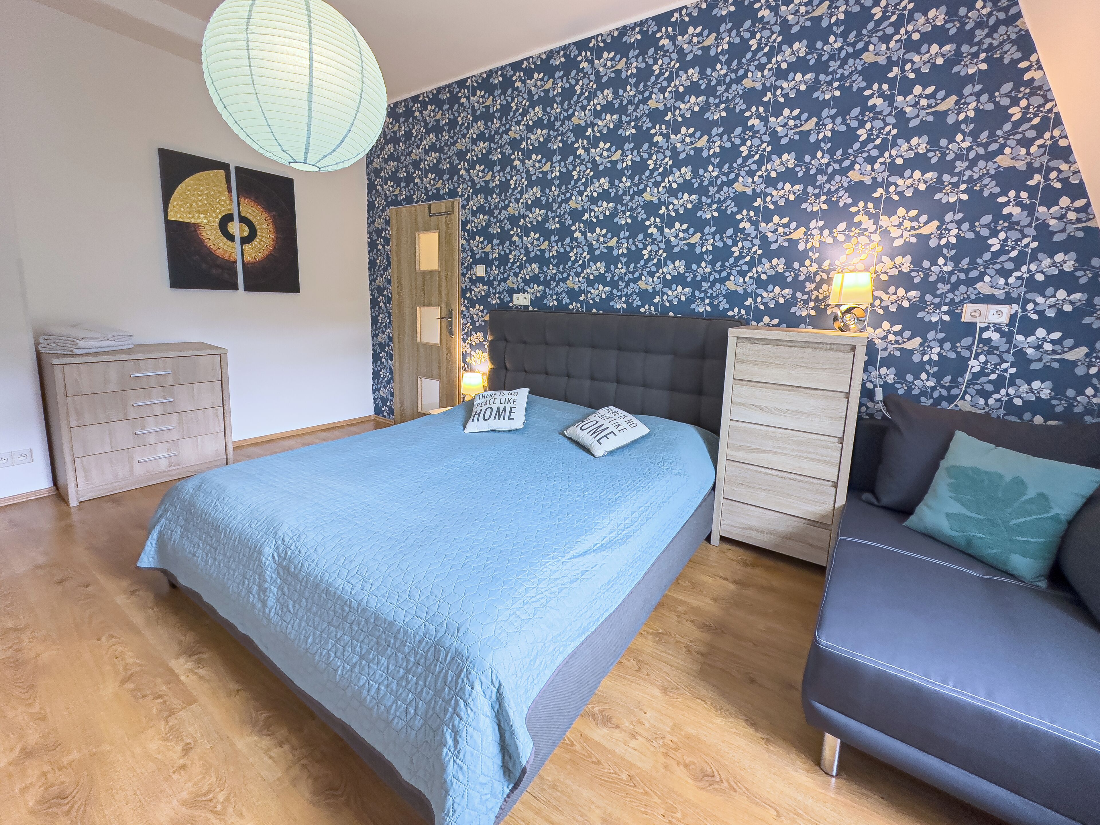 A bedroom with a bed, a sofa, a dresser, and a nightstand.