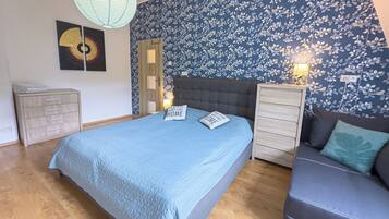 A bedroom with a bed, a sofa, a dresser, and a nightstand.