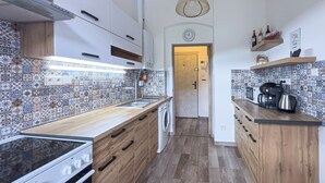 Eine Küche mit gemustertem Fliesenspiegel, Holzschränken, einem Herd, einer Spüle und einer Kaffeemaschine.