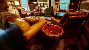 A cozy cabin interior with a leather sofa, a wooden coffee table, and a fireplace.