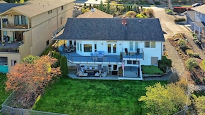 Ein zweistöckiges Haus mit überdachter Terrasse, einem eingezäunten Garten und einer gepflegten Grünfläche.