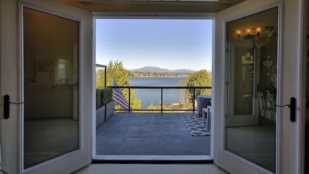 Ein Balkon mit Blick auf einen See und Berge, mit einer kleinen amerikanischen Flagge und einem Blumentopf.