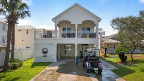 A two-story building with a balcony, a garage, and a golf cart in front.