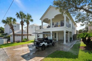 A two-story house with a covered porch and a golf cart parked in front.