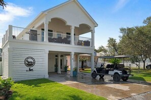 A two-story house with a covered porch and a golf cart parked in front.