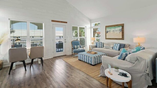 A spacious living room with a high ceiling, large windows, a sofa set, a coffee table, and a chair. - Casa Mimosa: Your Private Beach Escape with Pool, Bikes & Steps to the Sand (Santa Rosa Beach)